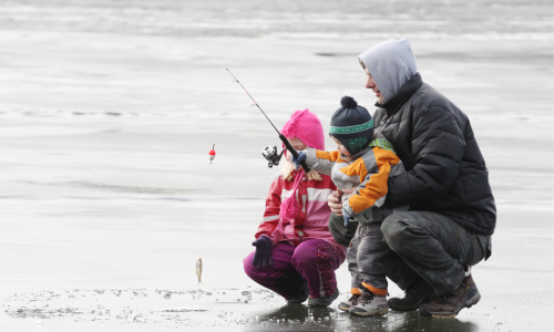 Parent ice fishing with two kids